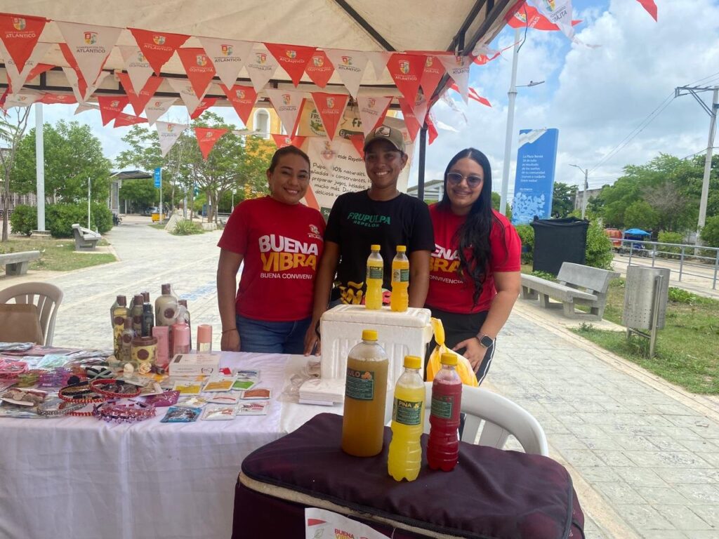 Experiencia Tres emprendedoras junto a su puesto de pulpas de fruta y jugos naturales en una feria comunitaria