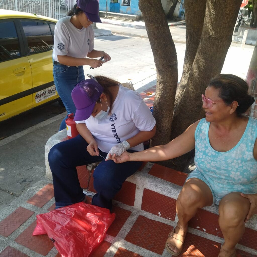 Experiencia Jornada de detección de dengue en la calle: una integrante del equipo atiende a una vecina del barrio.