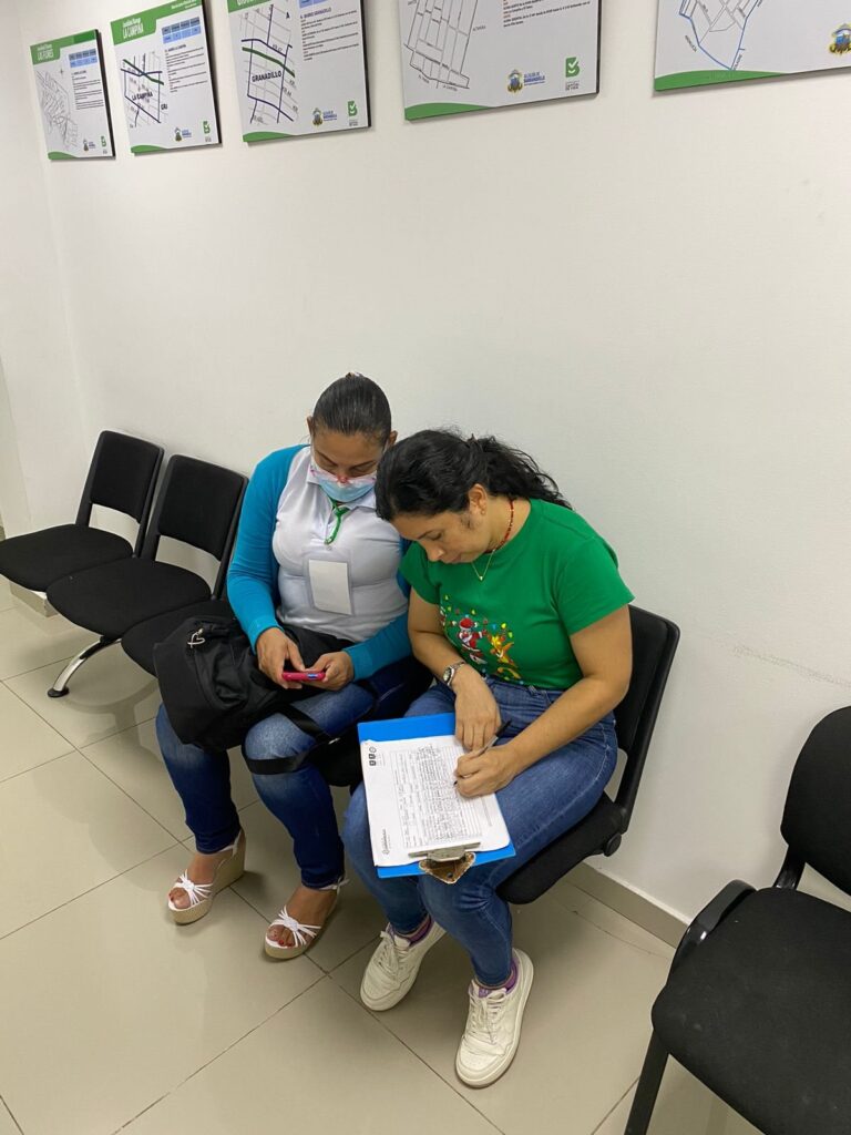 Una profesional de la Fundación acompaña a una mujer mientras diligencia un formato de atención.